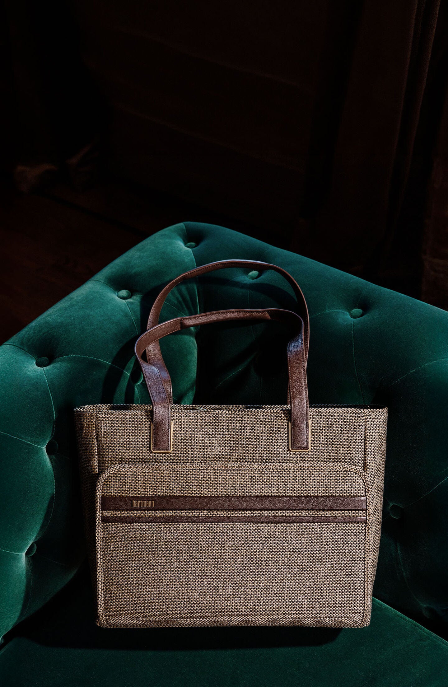 Tweed Carryall Tote is laying on a velvet couch. Click here to shop now.